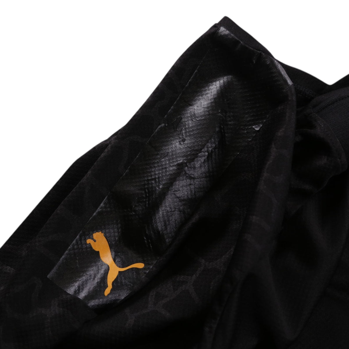Close-up of orange Puma logo on sleeve against dark tonal camouflage print