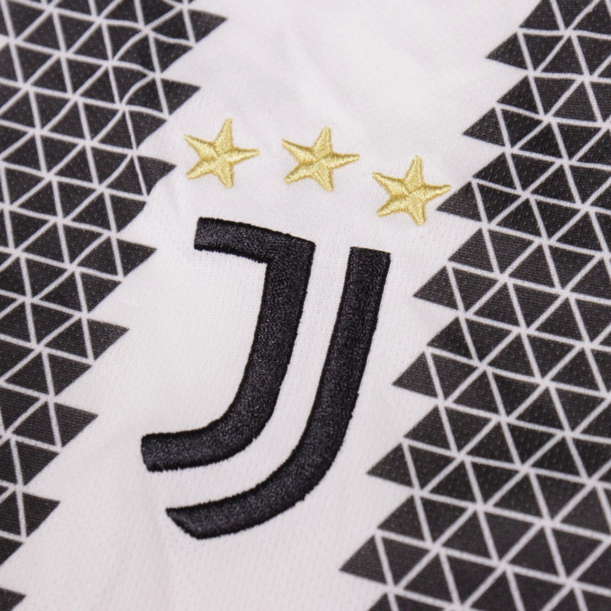Close-up of the Juventus crest with three gold stars on the shirt