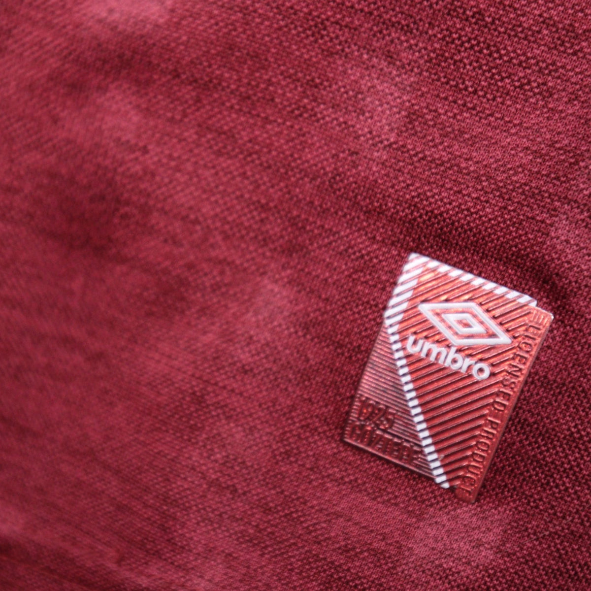 Close-up of the Umbro manufacturer tag on the maroon fabric of the shirt