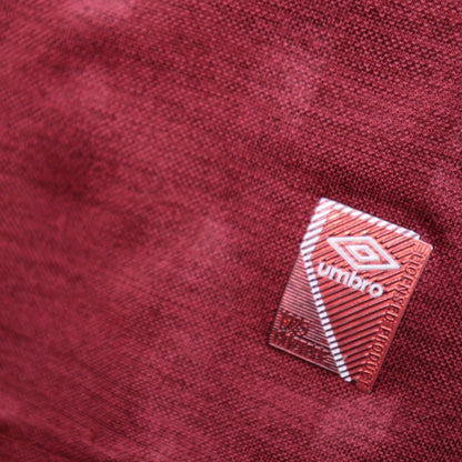 Close-up of the Umbro manufacturer tag on the maroon fabric of the shirt