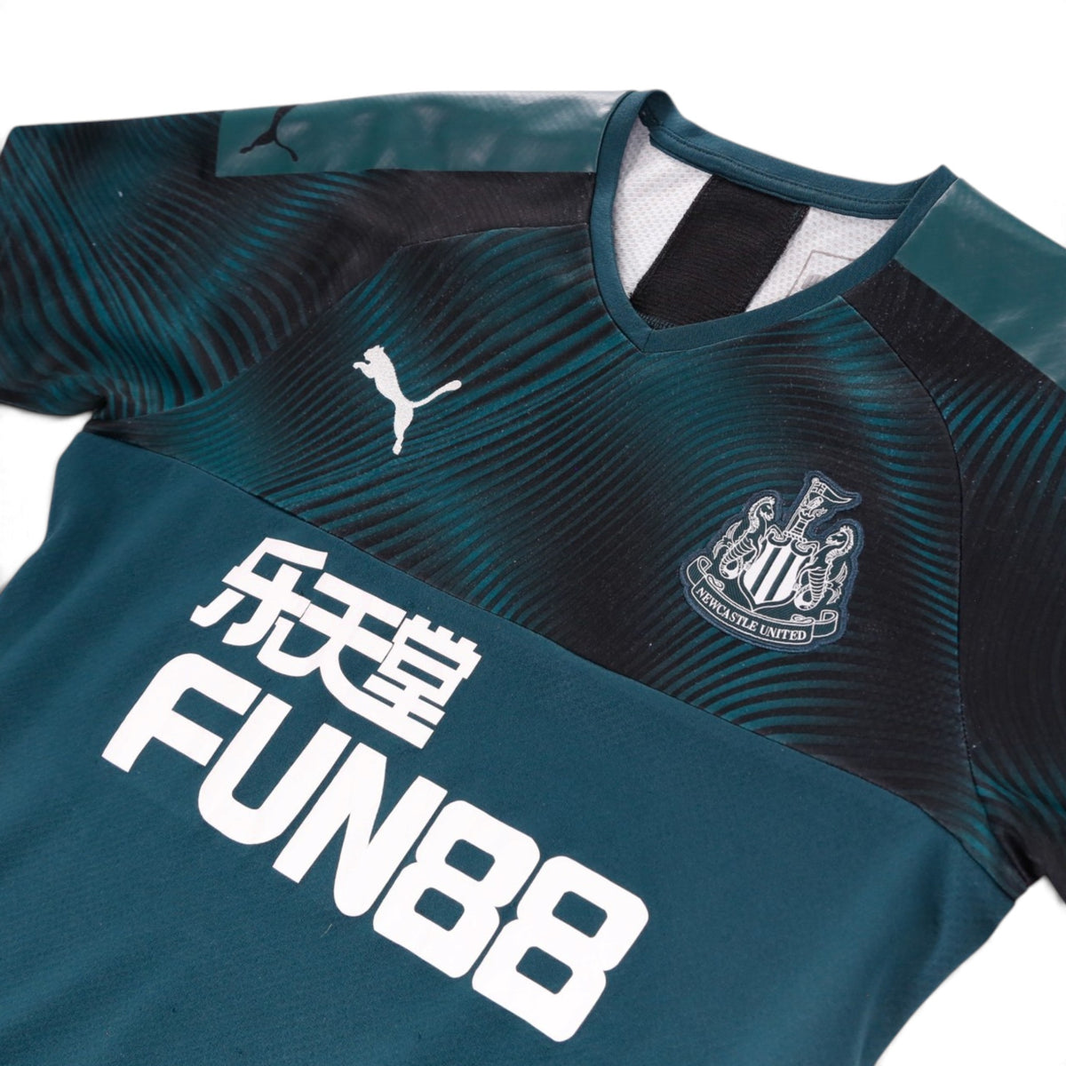 Close-up of Newcastle United crest and Puma logo on chest of away shirt