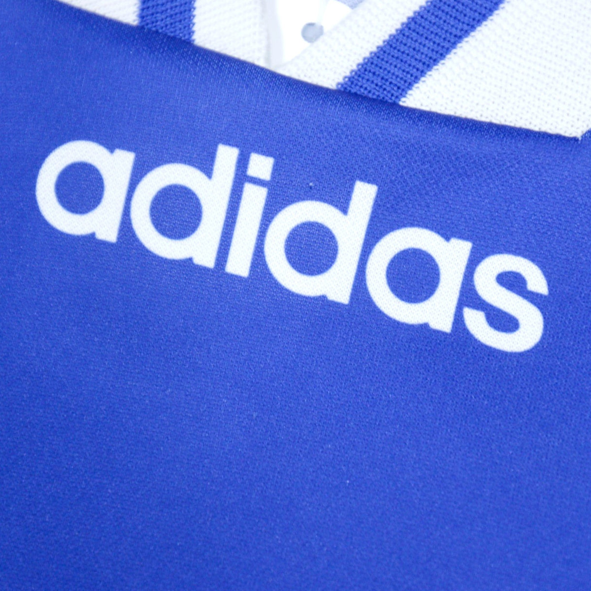 Close-up of the adidas logo printed beneath the V-neck collar