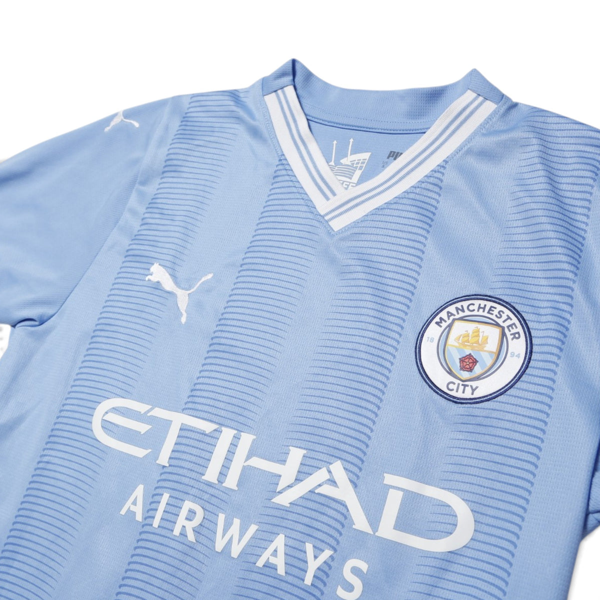 Close-up of Manchester City 2023/24 home shirt collar, crest and sponsor detail