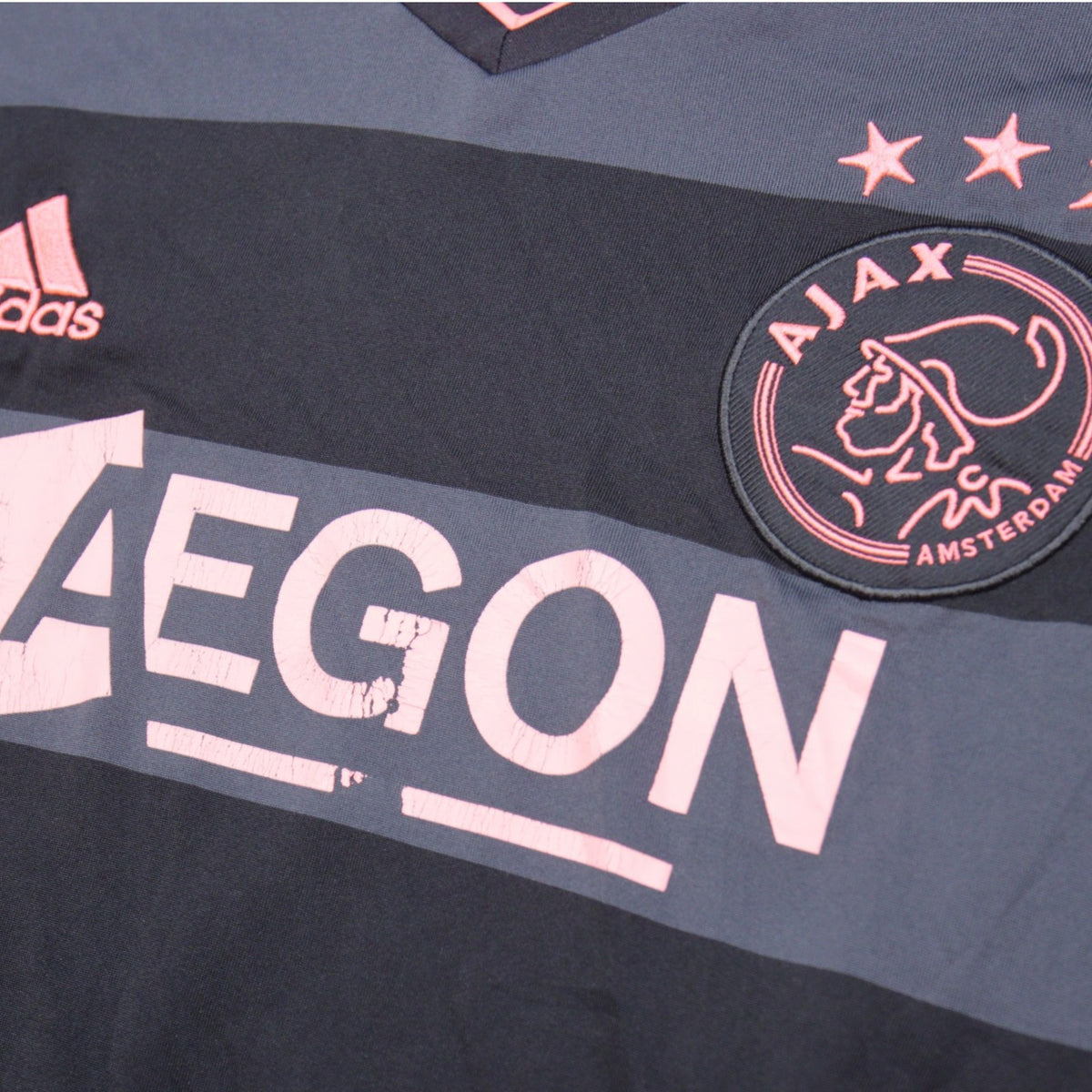 Close-up of Ajax crest, three stars and AEGON sponsor print