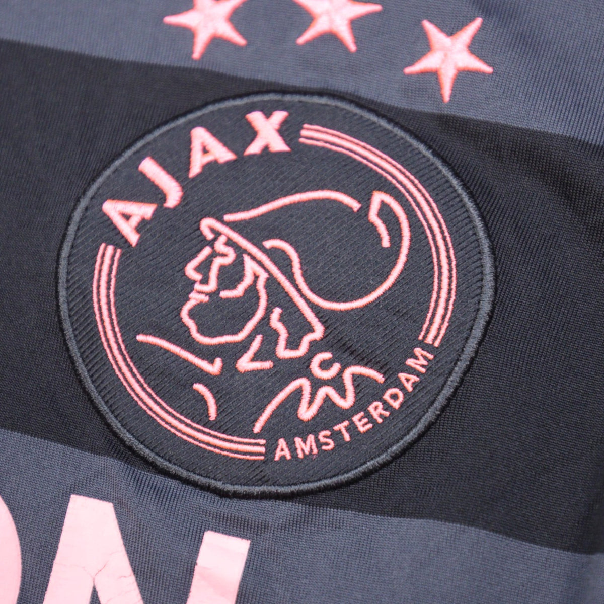 Close-up of embroidered Ajax crest with cracking visible on adjacent print