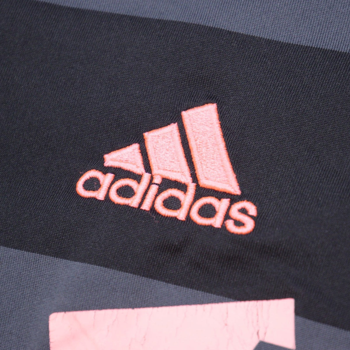 Close-up of adidas logo on chest with pink embroidery