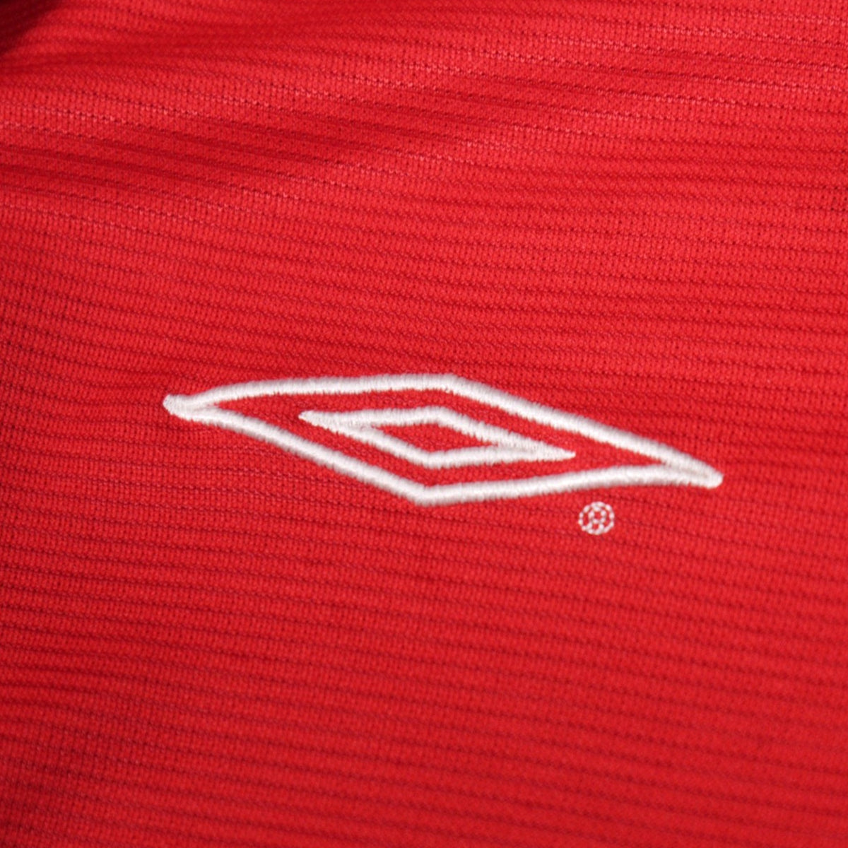 Close-up of the embroidered Umbro diamond logo on the shirt