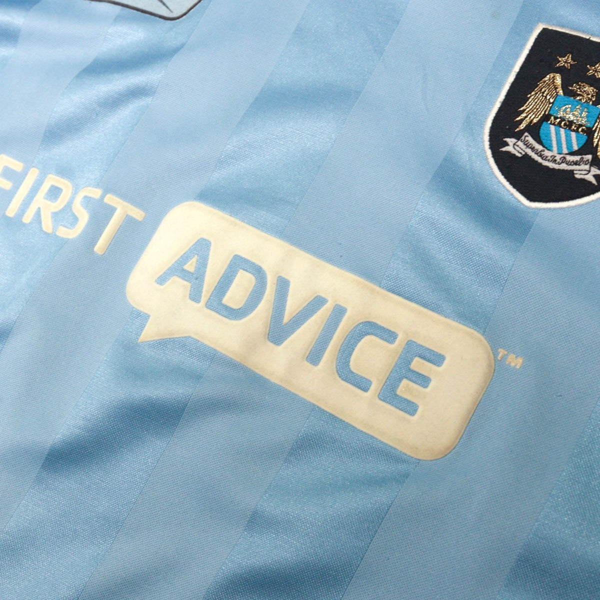 Close-up of First Advice sponsor and Manchester City crest on the chest