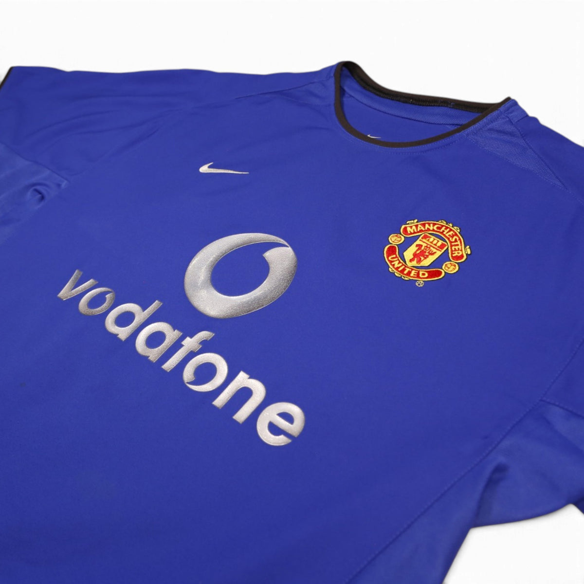Close-up of Nike logo, Vodafone sponsor and Manchester United crest on front of shirt