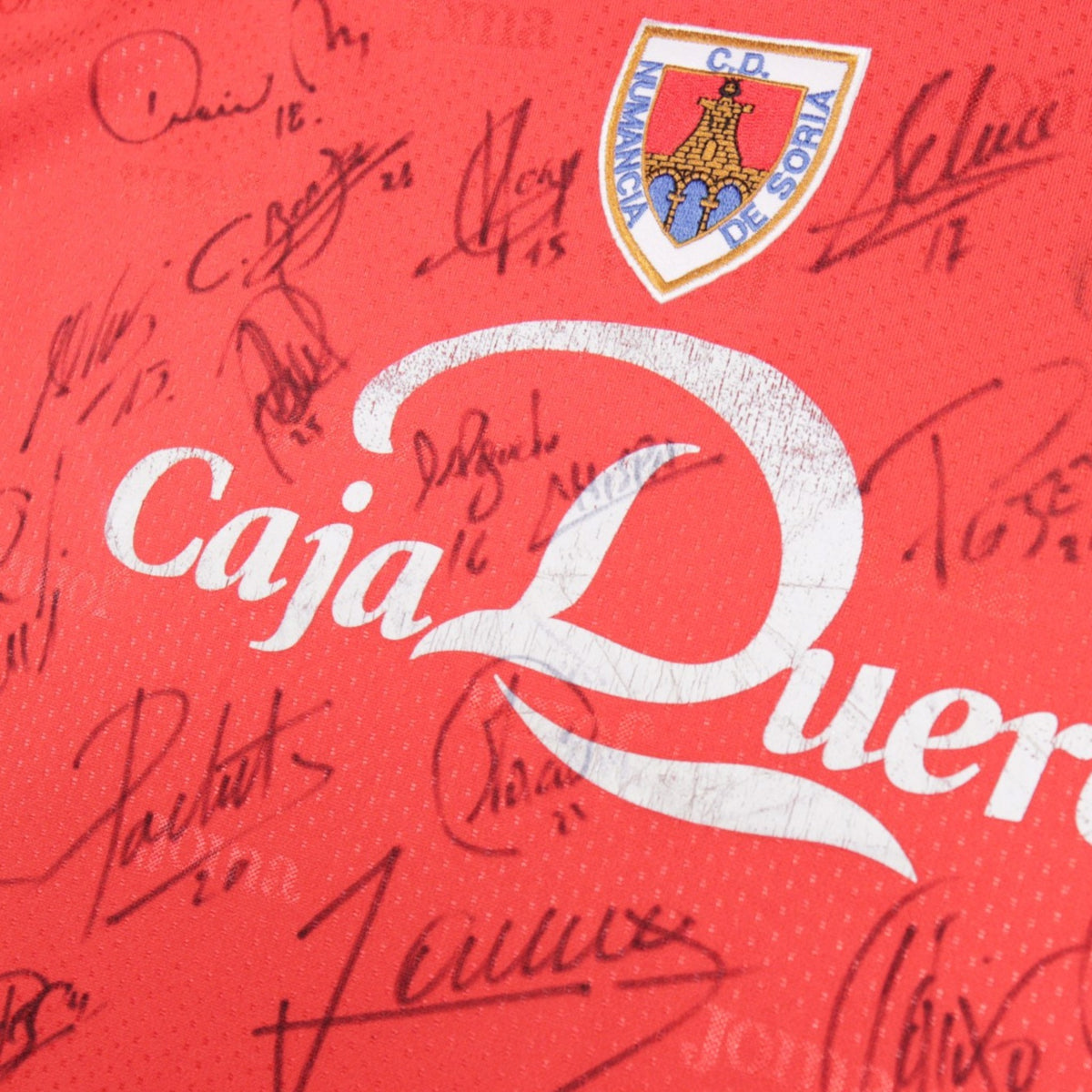 Close-up of Numancia crest and signatures on front of shirt