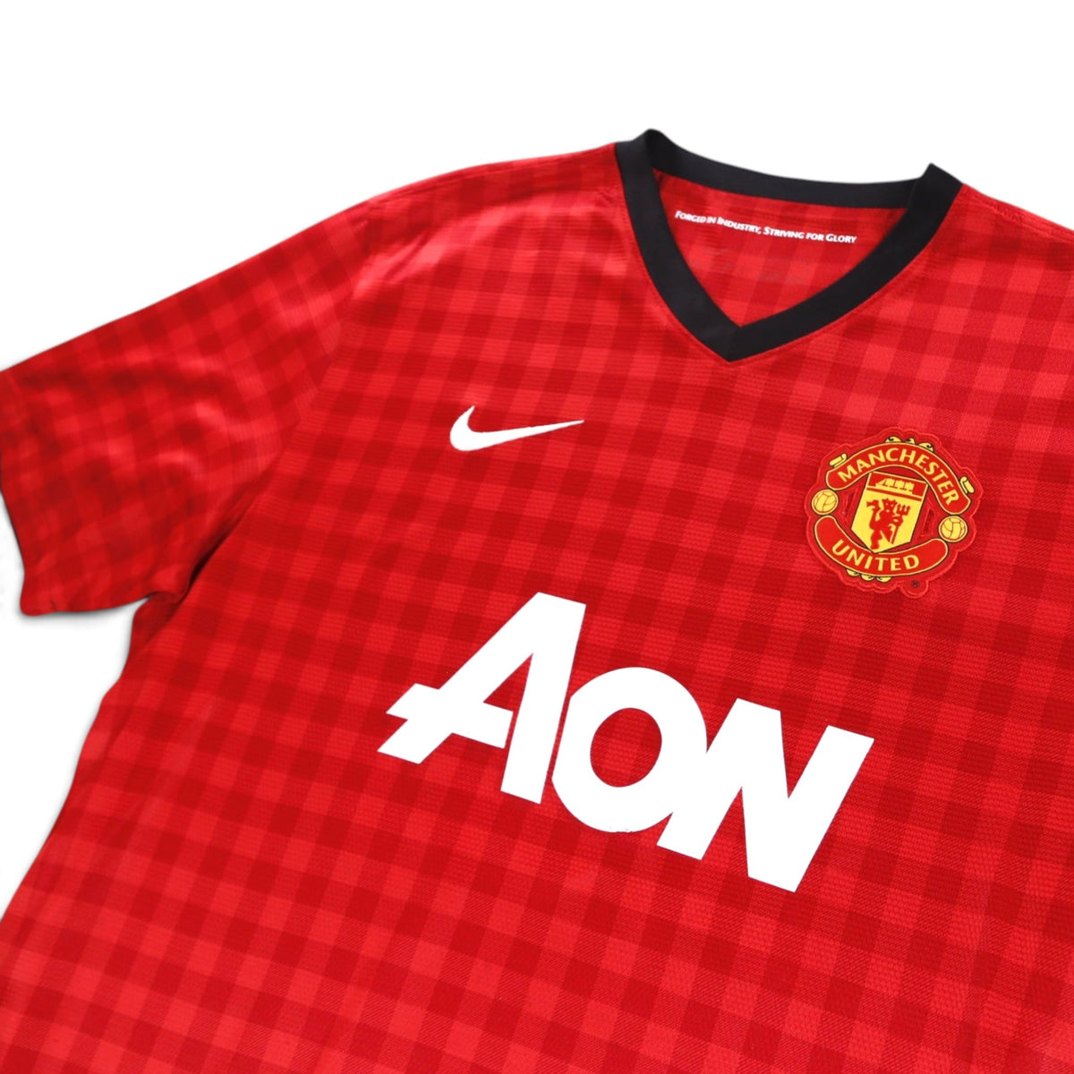 Close-up of the Manchester United crest, Nike swoosh and AON sponsor on the chest