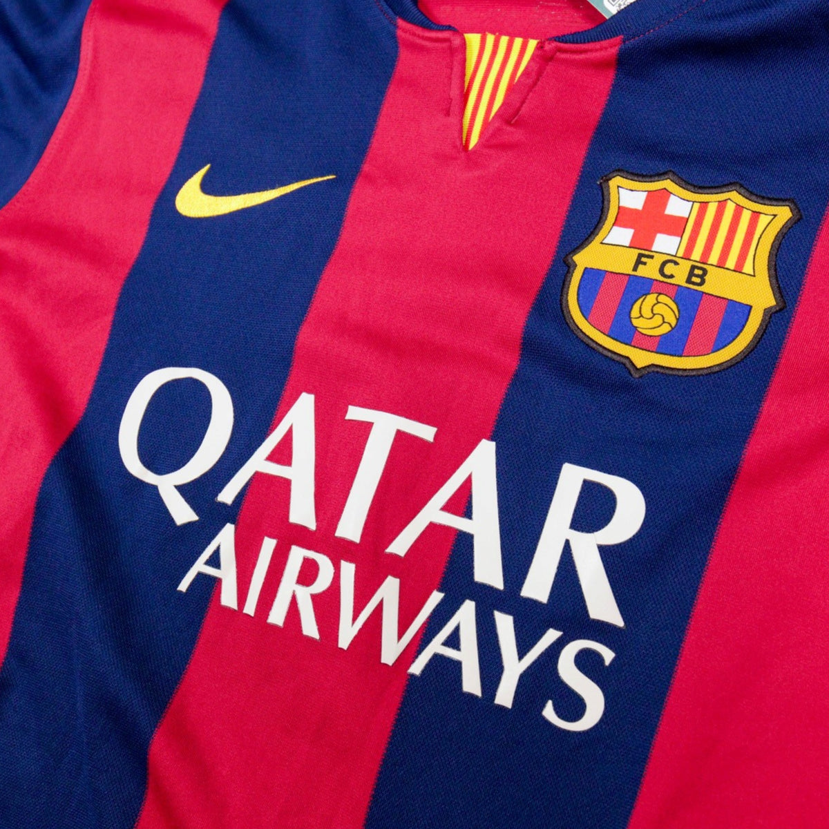 Close-up of Nike swoosh, FCB crest and v-neck collar with Catalan flag trim