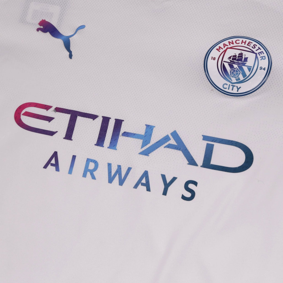 Close-up of chest showing Puma logo, Manchester City crest and Etihad Airways sponsor