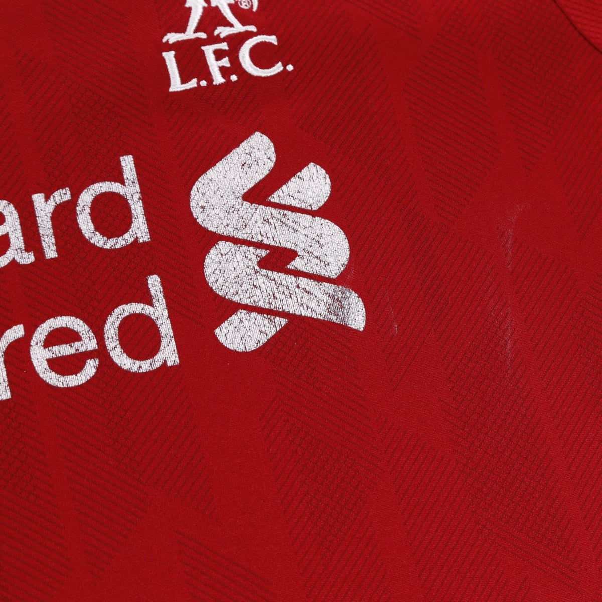 Close-up of L.F.C. crest and Standard Chartered sponsor with surface marks