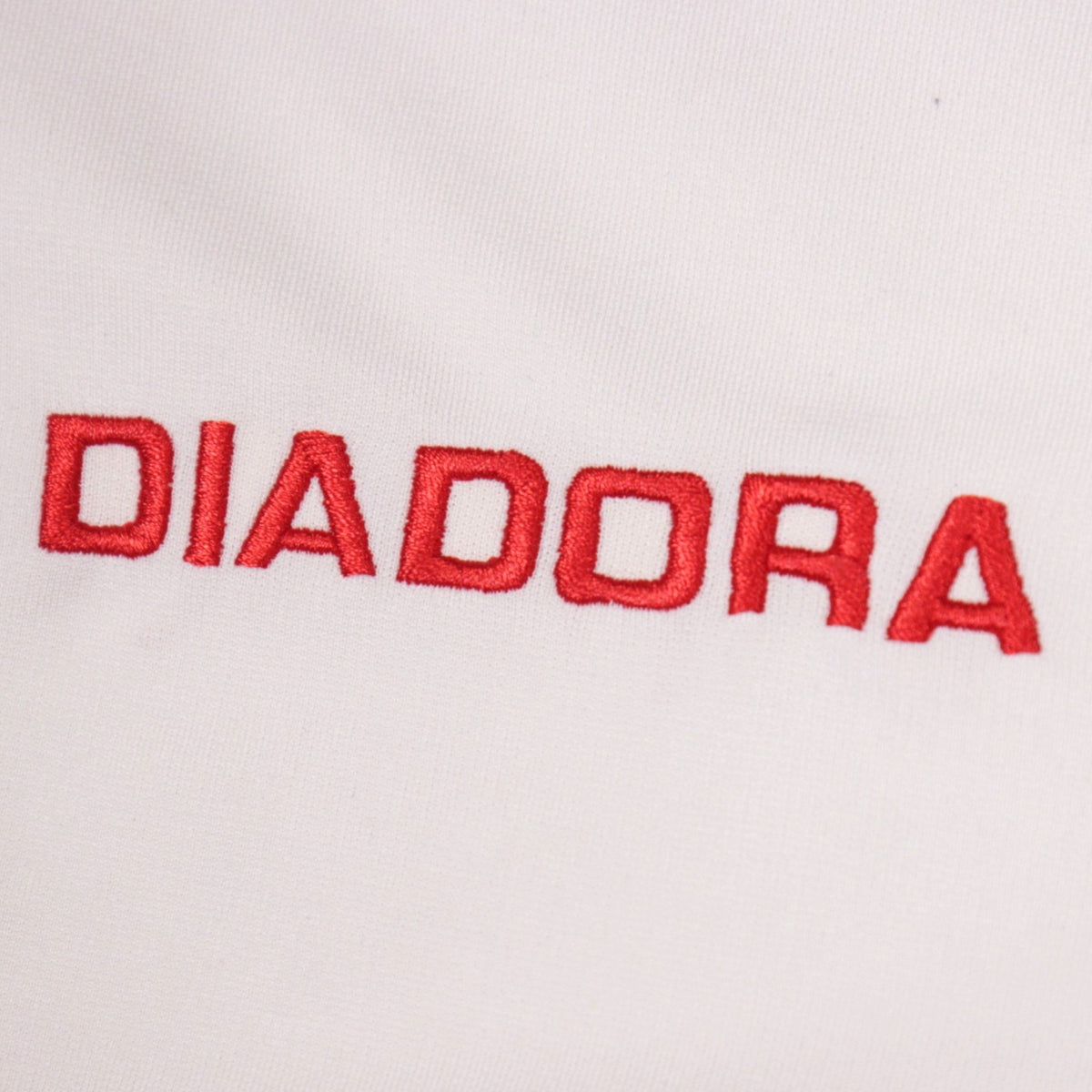 Close-up of the embroidered Diadora logo on the shirt front