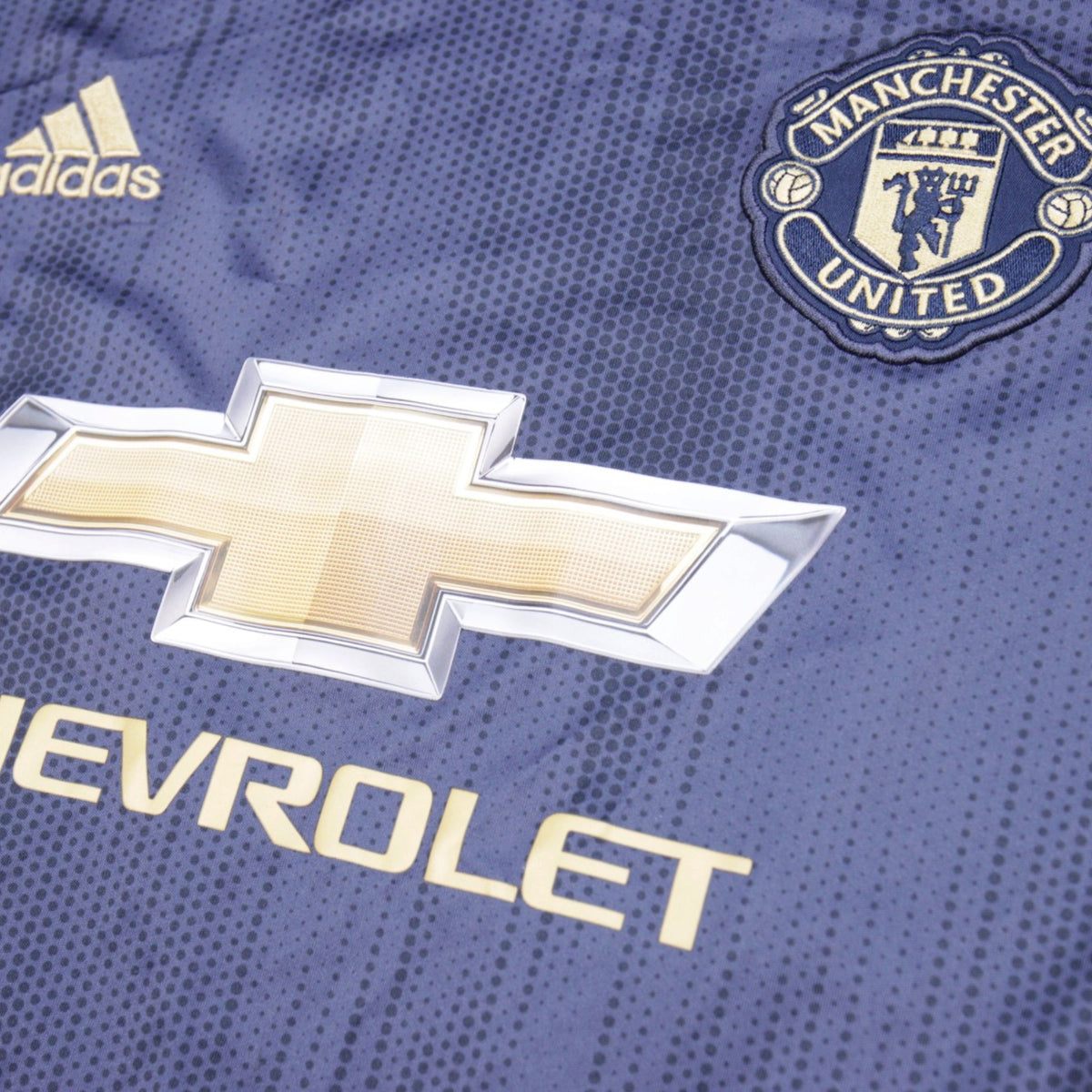 Close-up of adidas logo, Manchester United crest and Chevrolet sponsor on the chest