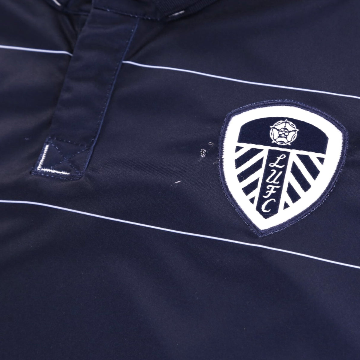 Close-up of the Leeds United crest and Macron logo on the chest with a small mark visible