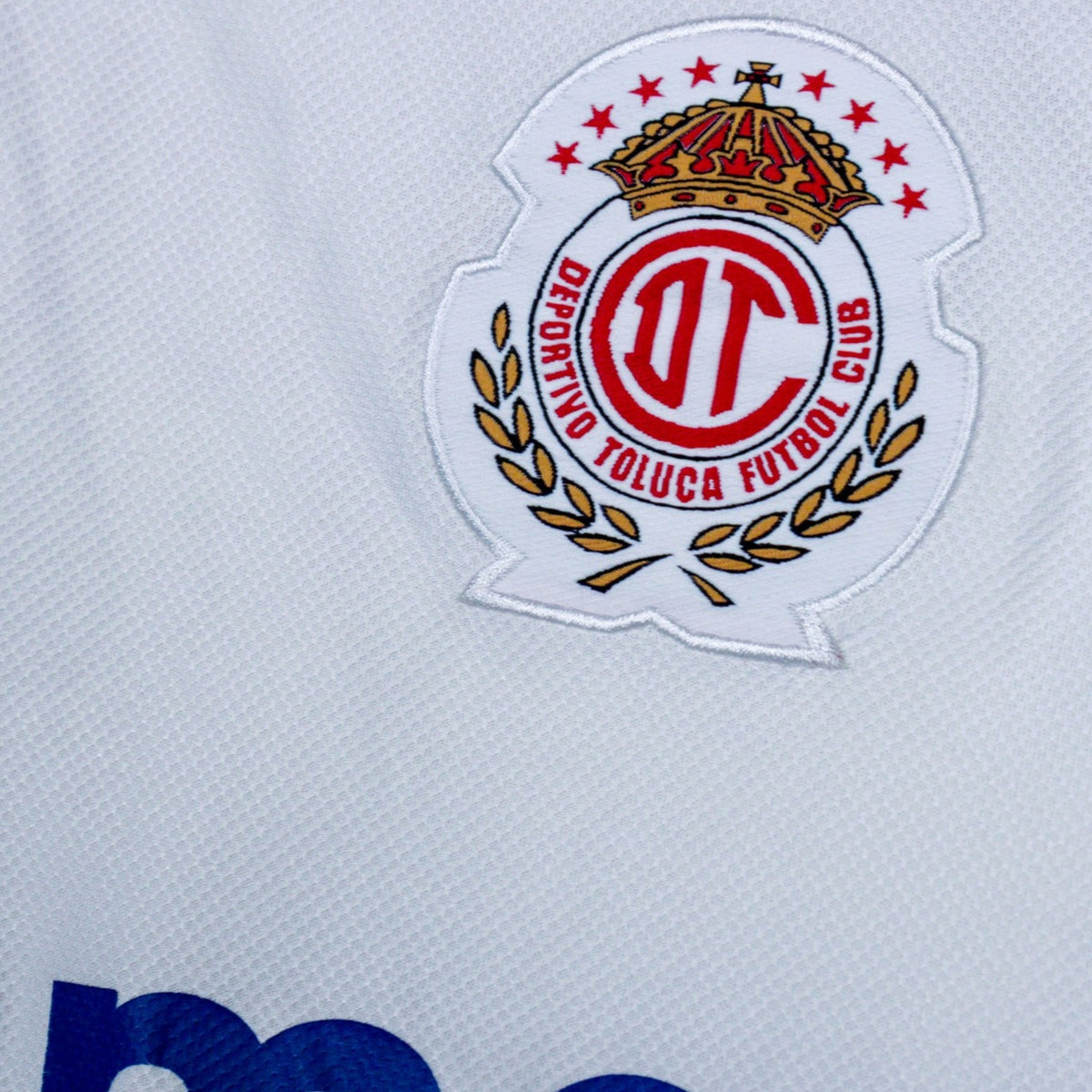 Close-up of the Deportivo Toluca crest showing crown, stars and laurel wreath