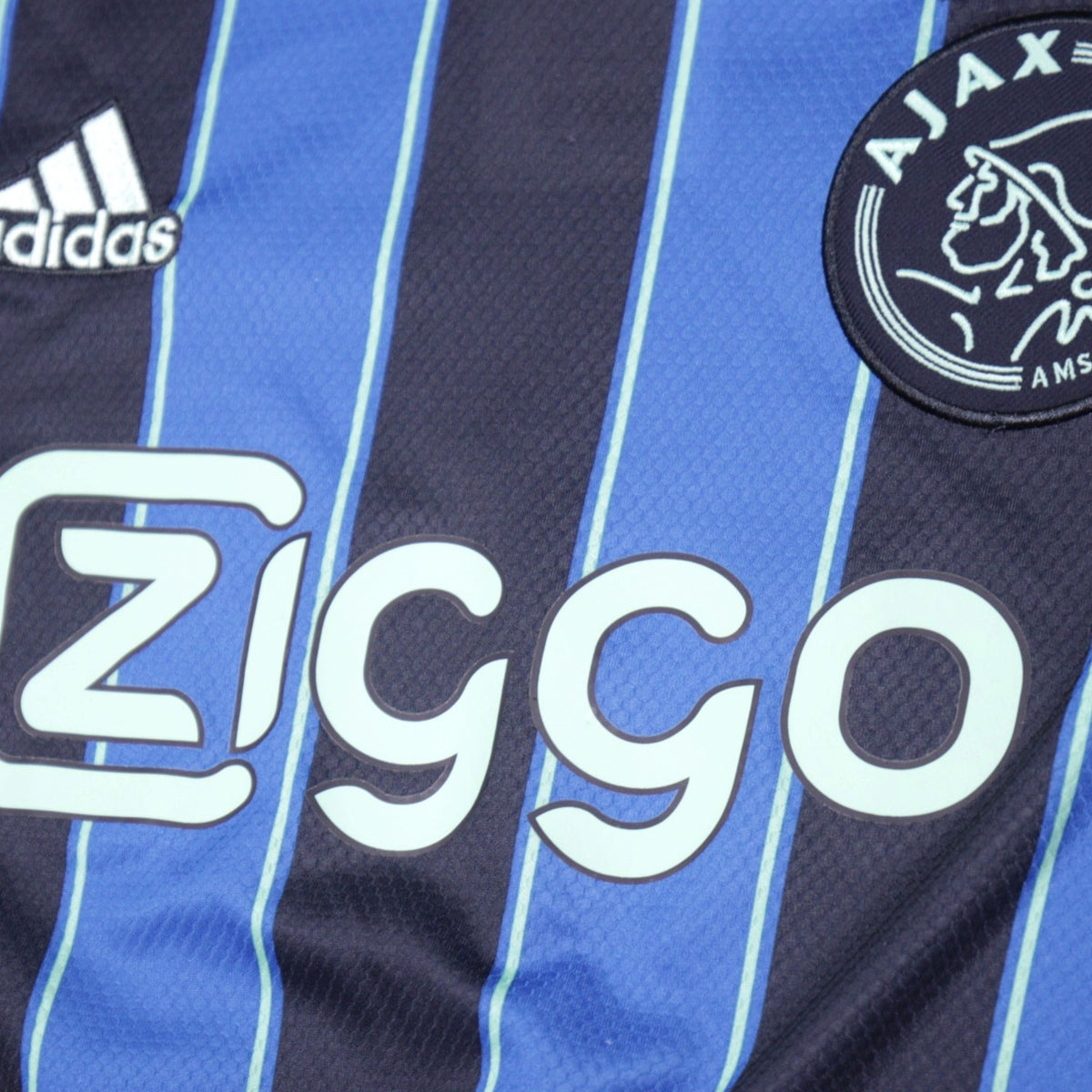 Close-up of Ajax crest and Ziggo sponsor logo on away shirt