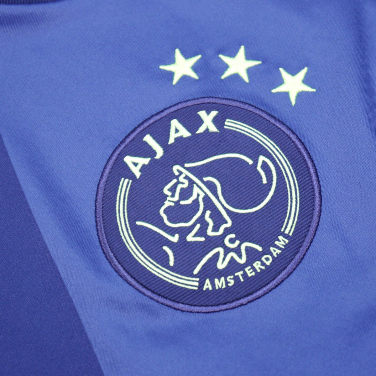 Close-up of Ajax club crest with three stars above it