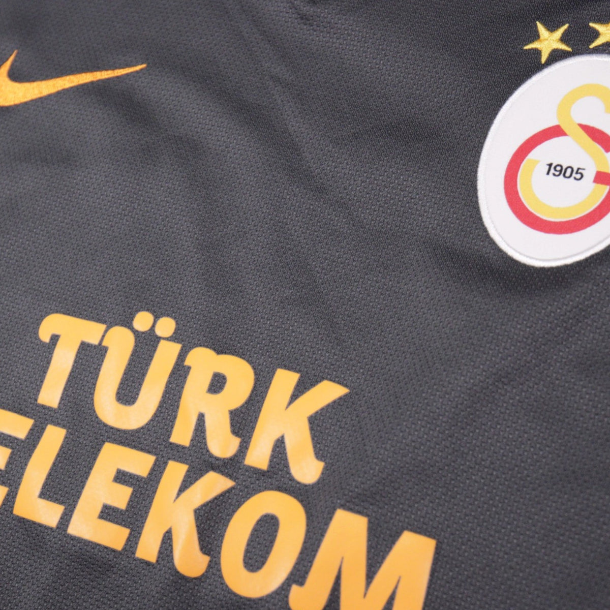 Close-up of the Galatasaray crest, three championship stars and Türk Telekom sponsor print