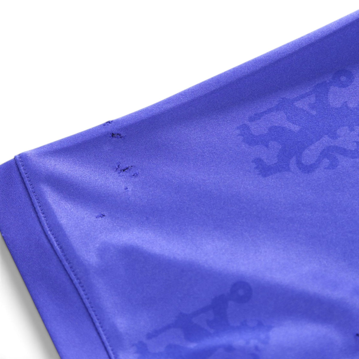 Close-up of the sleeve hem fabric showing small snags and the repeating lion motif