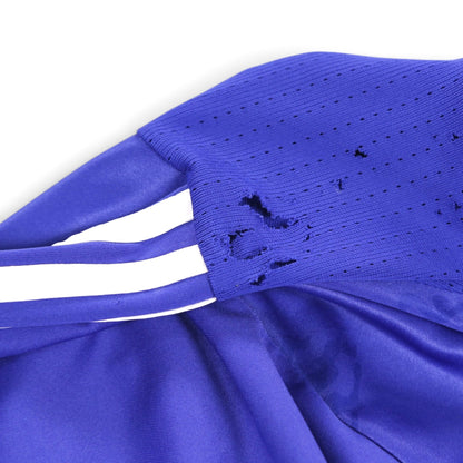 Close-up of a tear and small holes at the shoulder seam near the sleeve stripes
