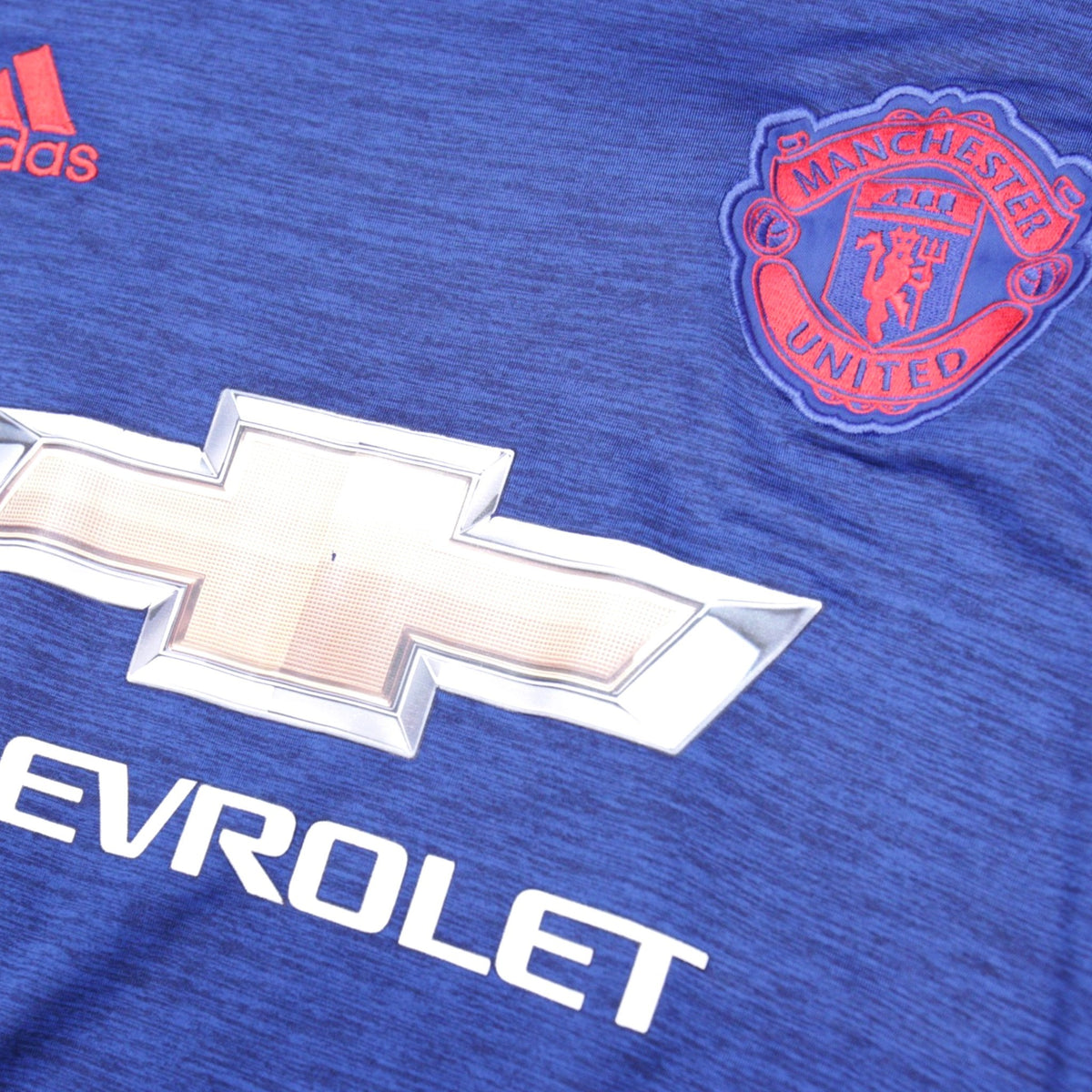 Close-up of Chevrolet sponsor and Manchester United crest on shirt front