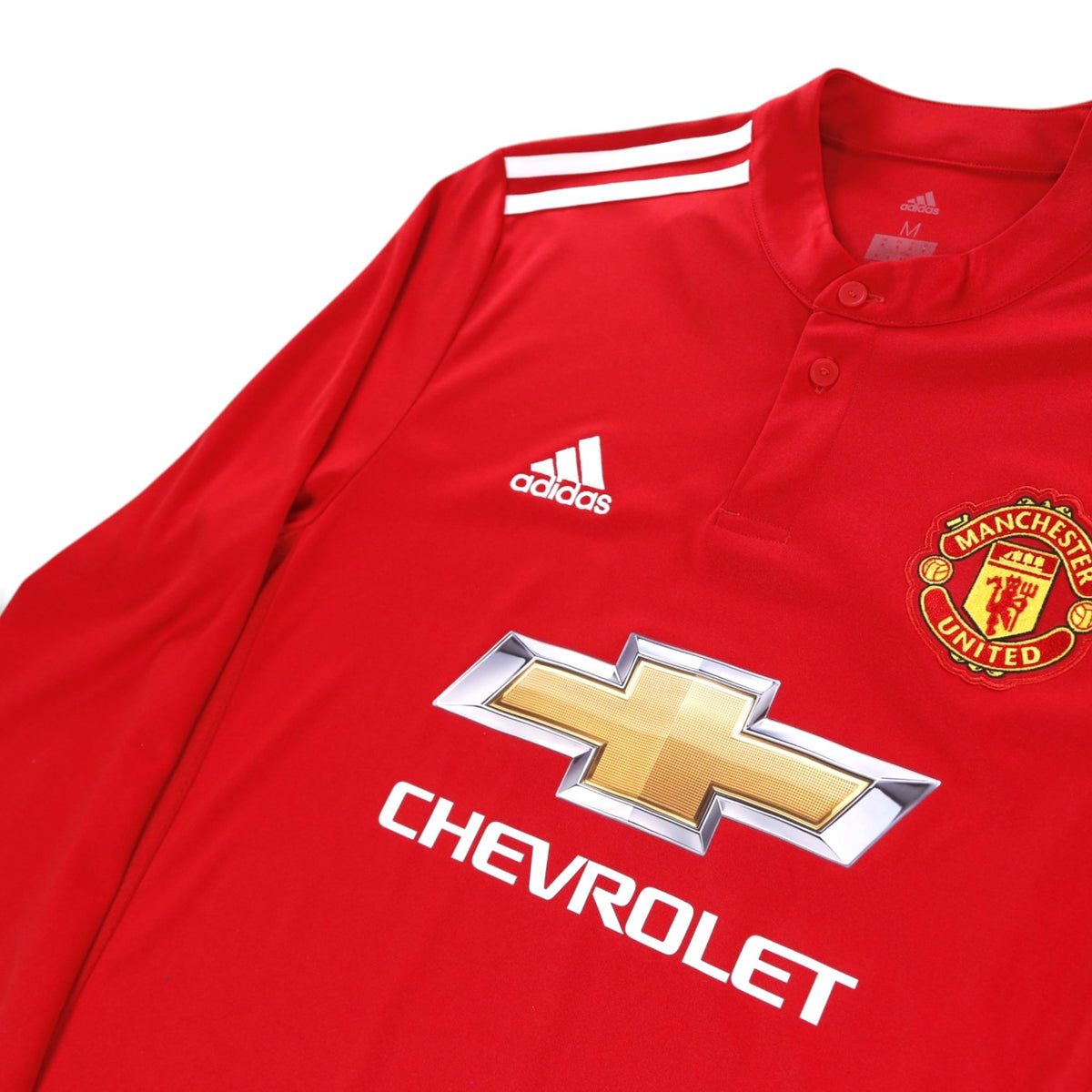 Close-up of adidas logo, crest and Chevrolet sponsor on Manchester United 2017/18 home shirt