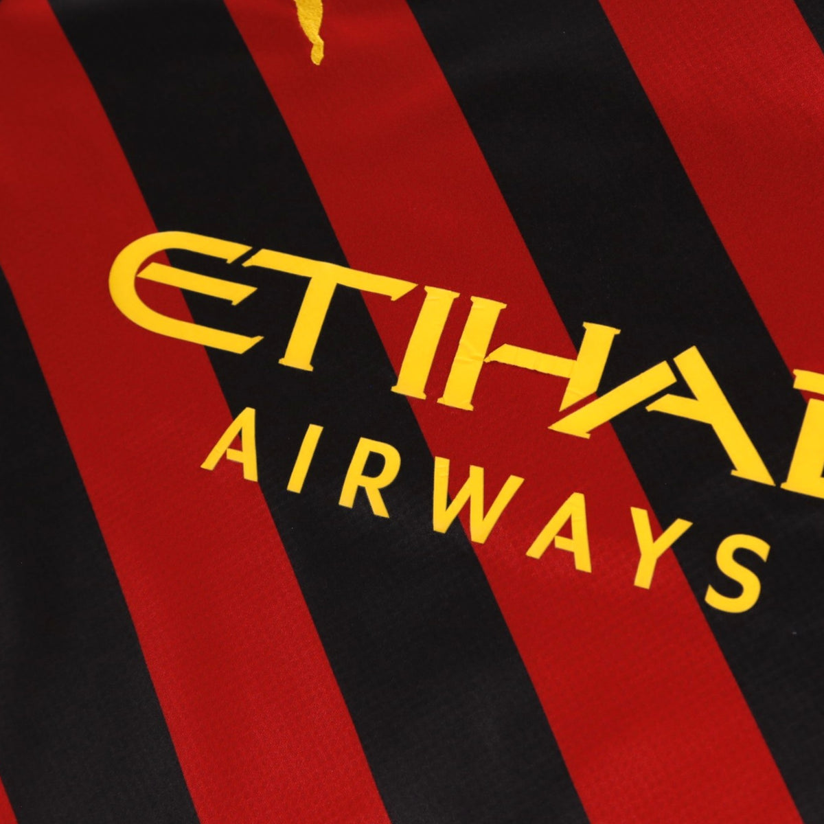 Close-up of the Etihad Airways sponsor on the red and black diagonal stripes