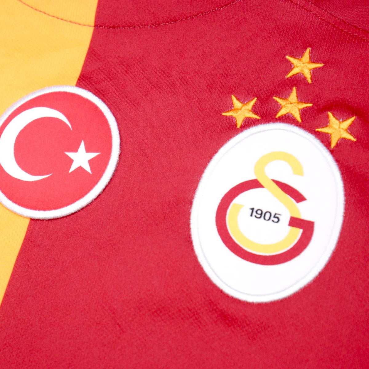 Close-up of the Galatasaray crest, Turkish flag badge and four championship stars