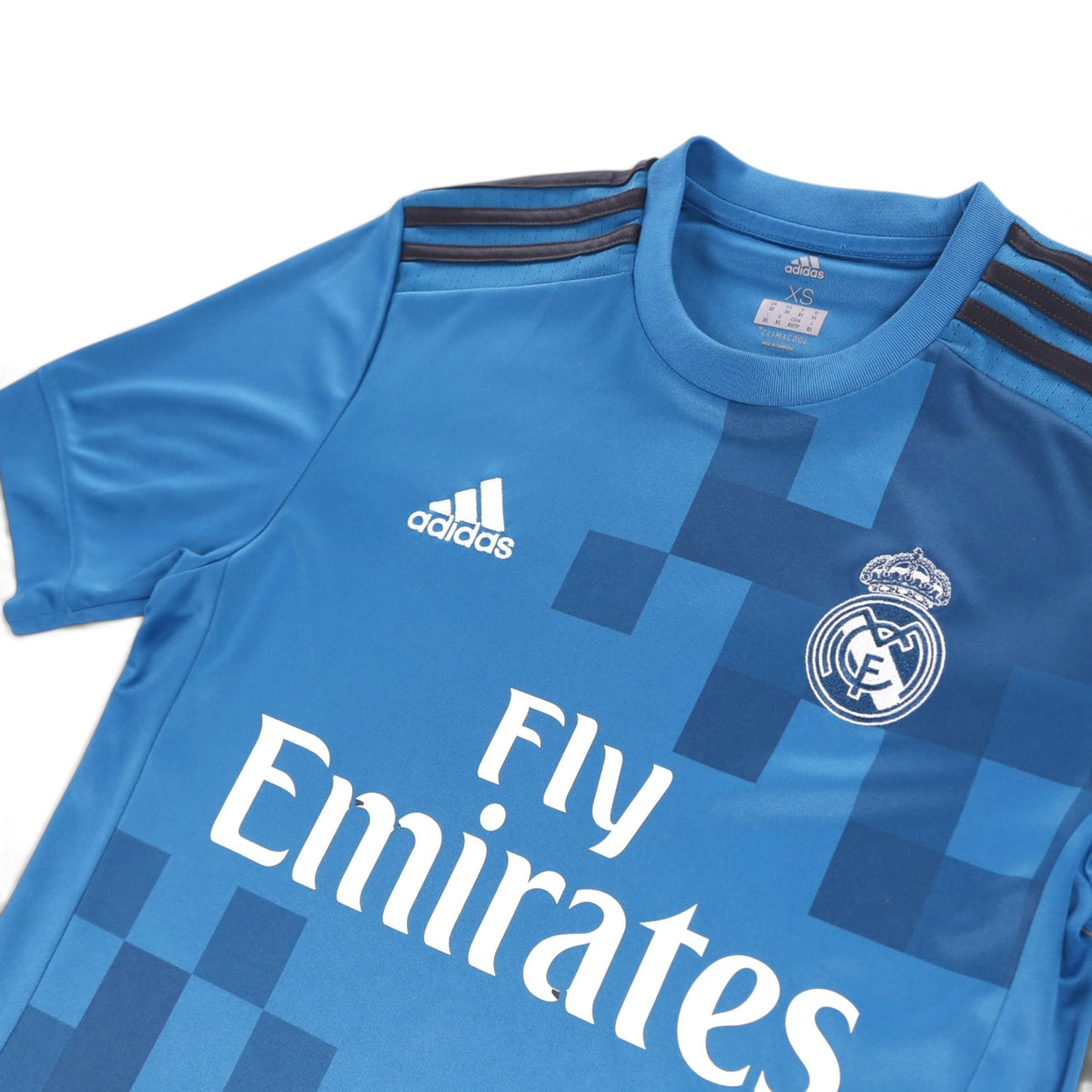 Close-up of the adidas logo, Real Madrid crest and XS neck label