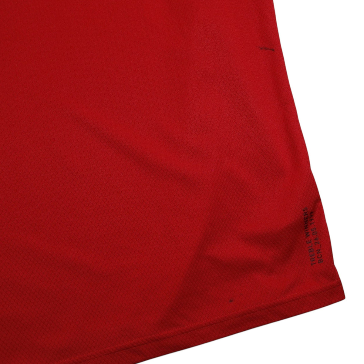 Close-up of Manchester United shirt hem showing 'Treble Winners BCN 26.05.1999' print