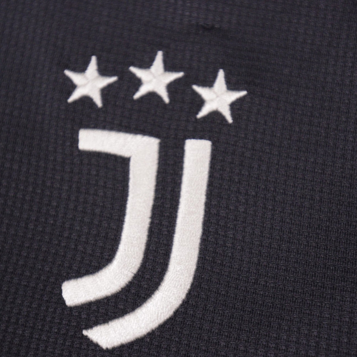 Close-up of the embroidered Juventus crest and three stars on the third shirt