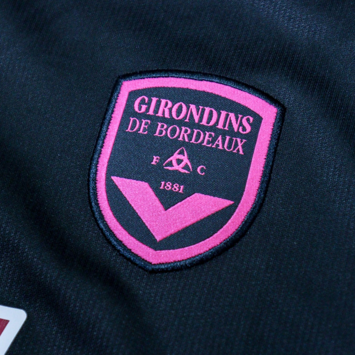 Close-up of the pink and black Girondins de Bordeaux crest reading 1881