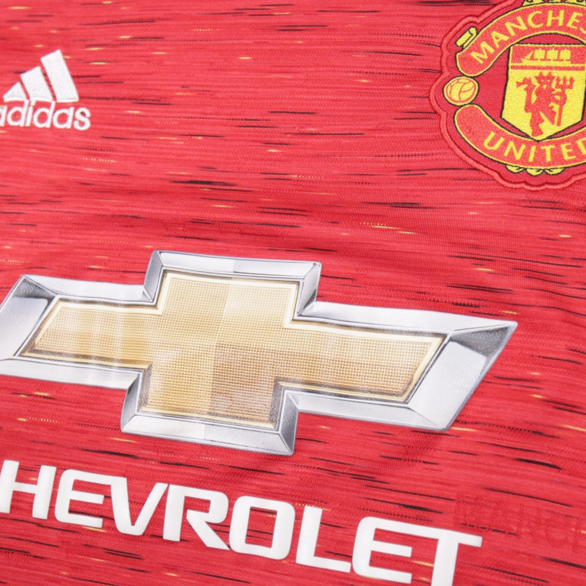 Close-up of adidas logo, crest and Chevrolet sponsor on Manchester United shirt