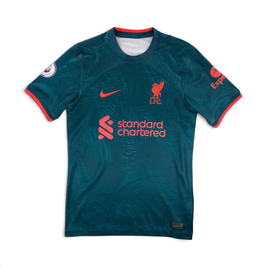 Liverpool 2022/23 third shirt front view, teal-green with coral trim and Standard Chartered sponsor