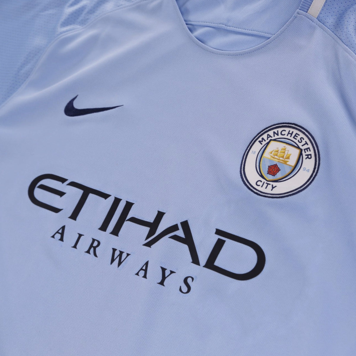 Close-up of Manchester City crest, Nike swoosh and Etihad Airways sponsor on the chest