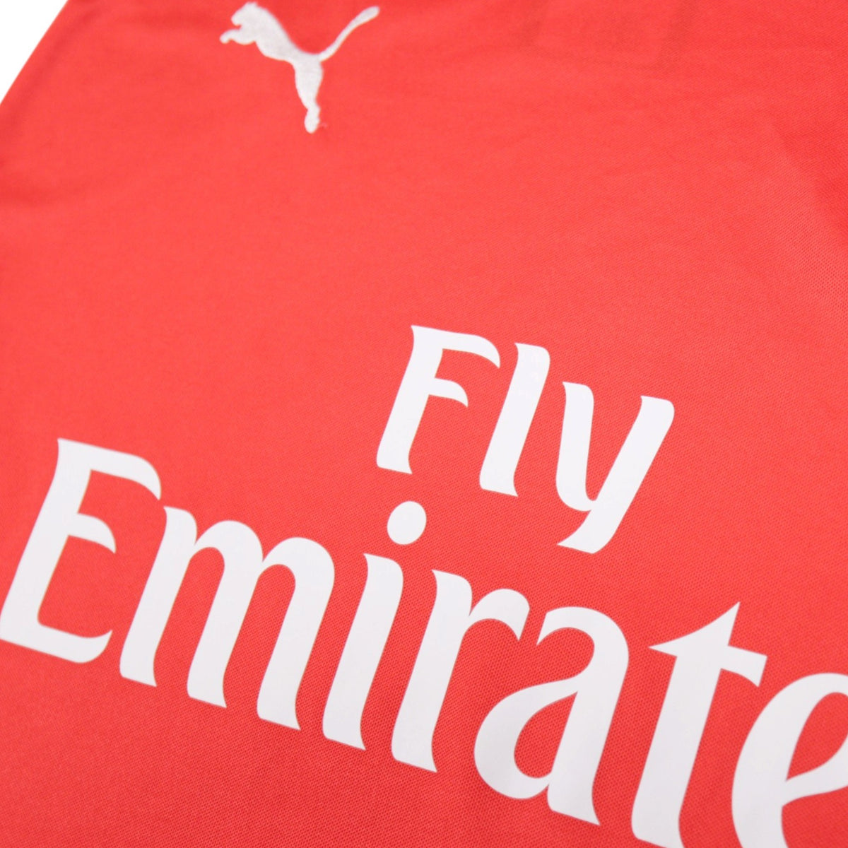 Close-up of the Fly Emirates sponsor print and Puma logo on the 2014/15 Arsenal home shirt
