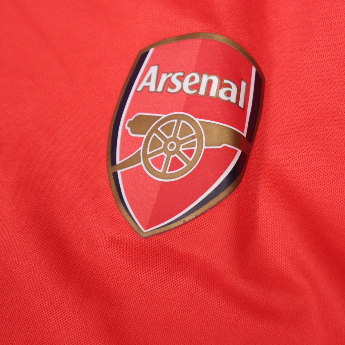 Close-up of the Arsenal club crest on the 2014/15 home shirt
