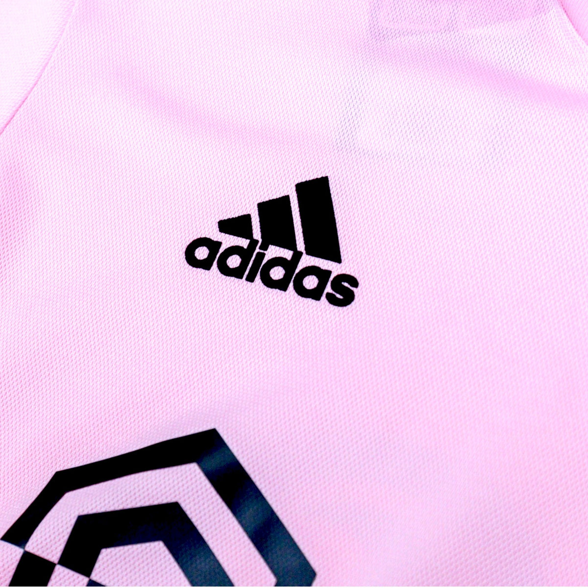 Close-up of the adidas logo on the chest of the pink shirt