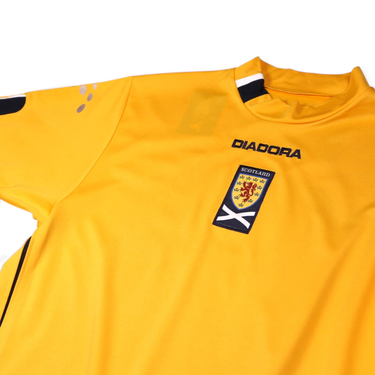 Close-up of Diadora logo, Scotland crest and collar detail on yellow third shirt
