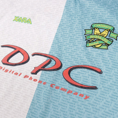 Close-up of Xara logo, DPC sponsor print and Norwich City centenary crest on the shirt front