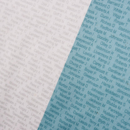 Close-up detail of the white and sky blue panel join showing the printed supporters' surname pattern