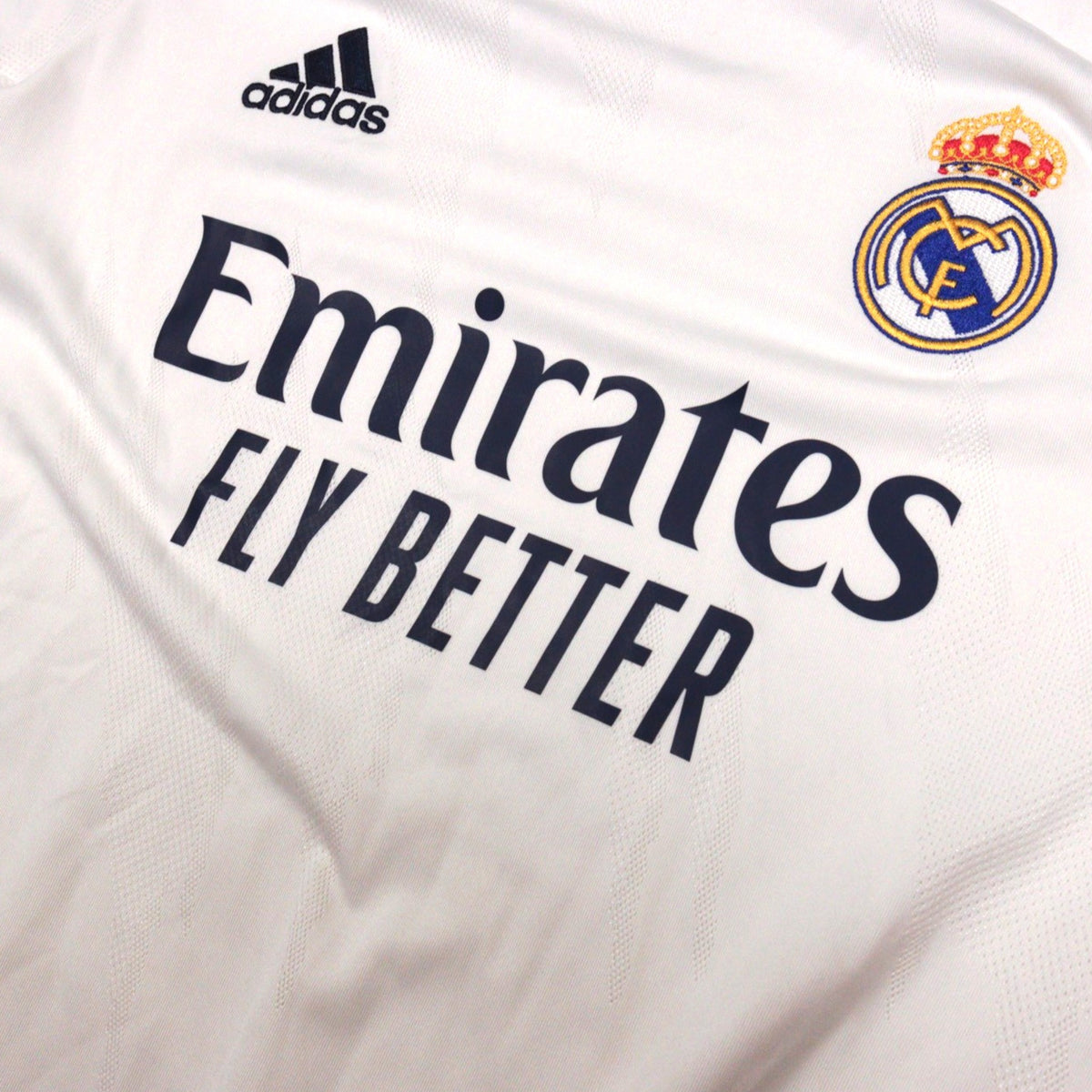 Close-up of adidas logo, Emirates sponsor and Real Madrid crest on chest