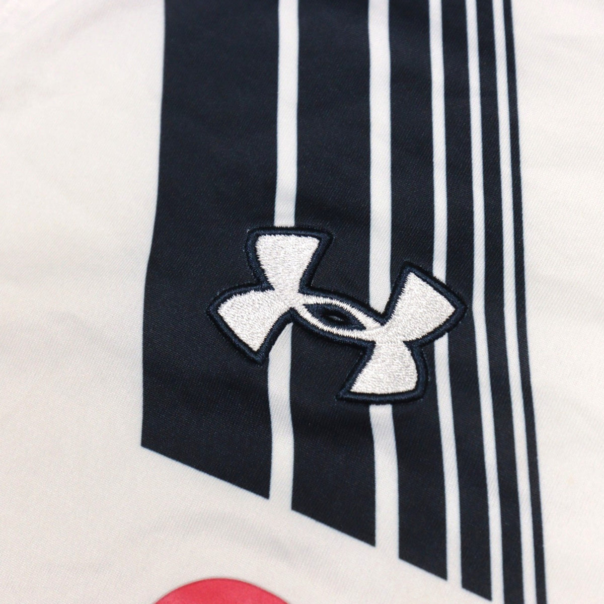 Close-up of the Under Armour logo stitched into the navy diagonal sleeve stripe