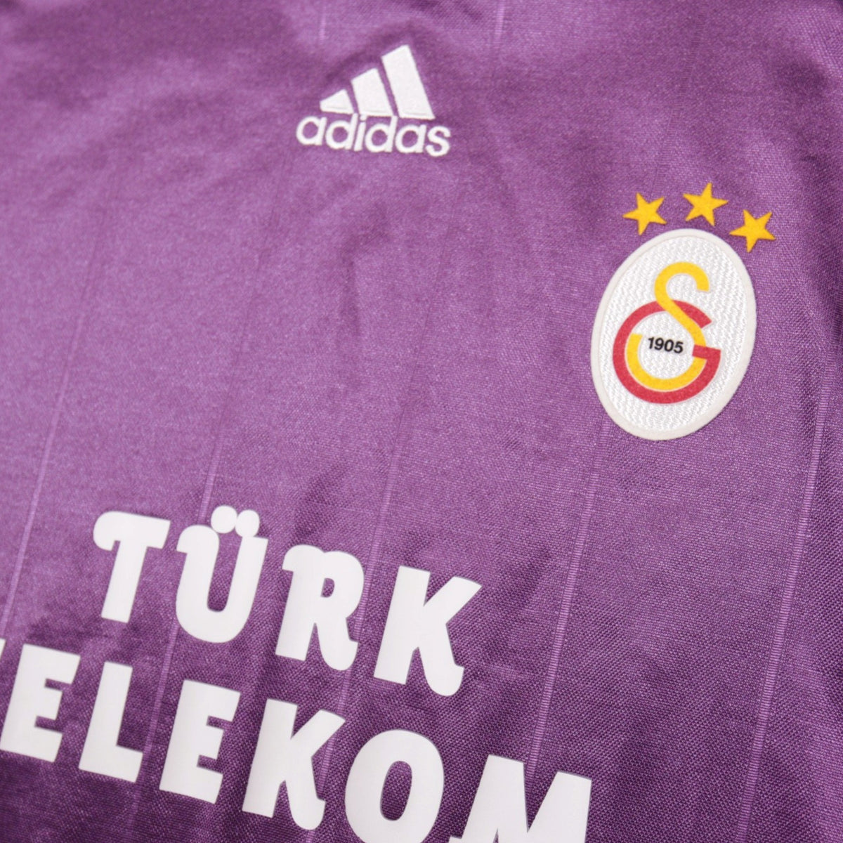 Close-up of adidas logo and Galatasaray crest with three stars on the shirt front