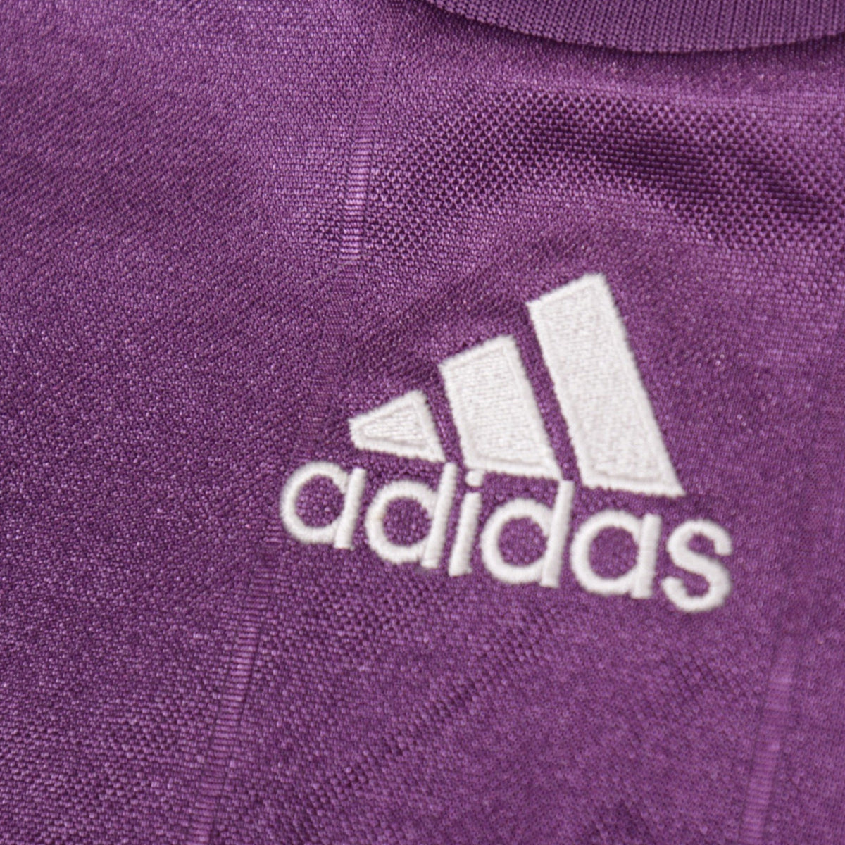 Close-up of the embroidered adidas logo on the shoulder of the shirt