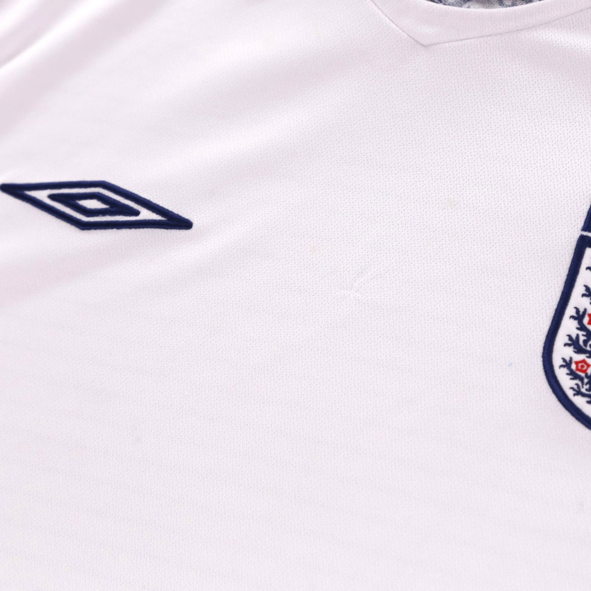 Close-up of Umbro logo and England crest on chest of home shirt