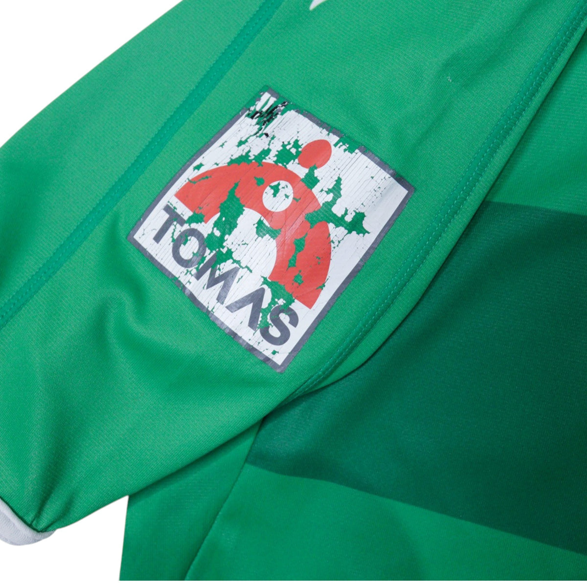 Close-up of a cracked Tomas patch on the sleeve of the shirt